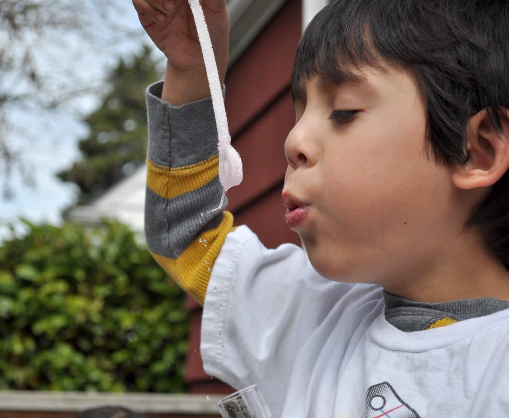 Child blowing soap bubbles with a bubble wand