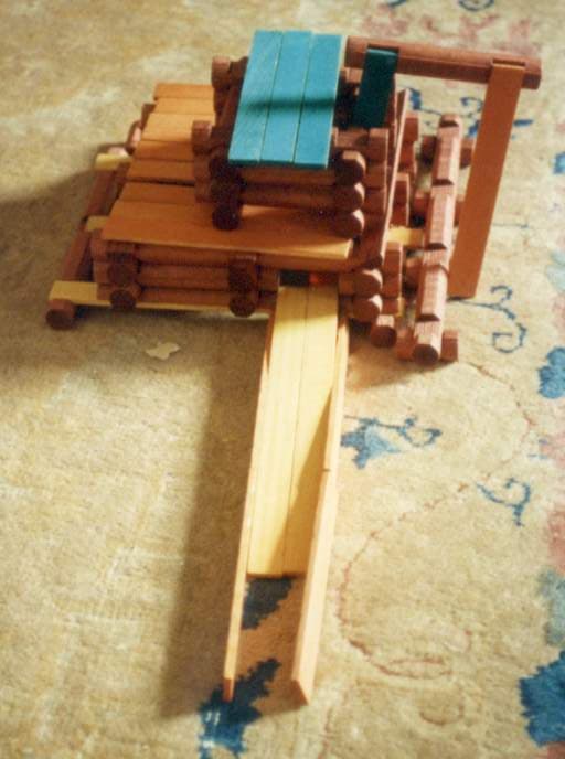A classic Lincoln Logs building set featuring notched wooden logs and a green roof piece.