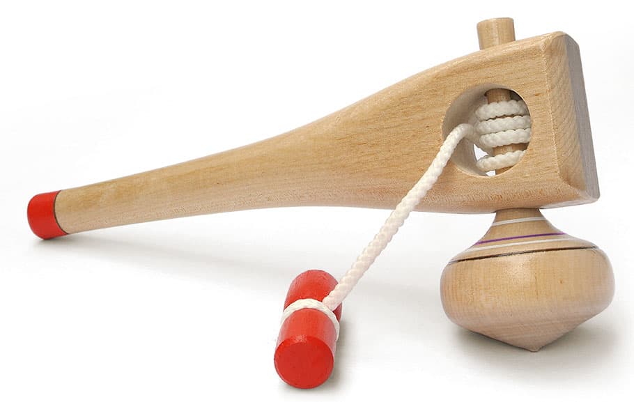 A classic wooden spinning top with a natural finish, centered on a plain background.
